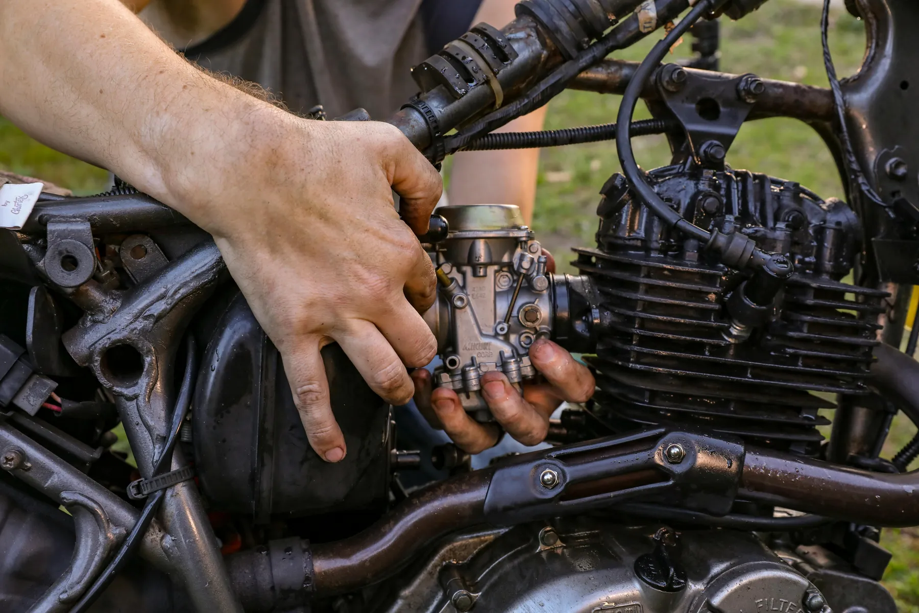 A carburetor being fitted to a motorcycle engine